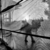 A black and white photo of a person walking through a tent