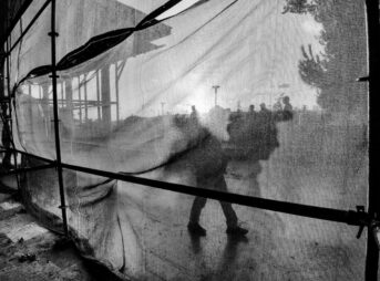 A black and white photo of a person walking through a tent