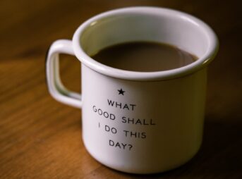 white and black ceramic cup filled with brown liquid on brown wooden sufface